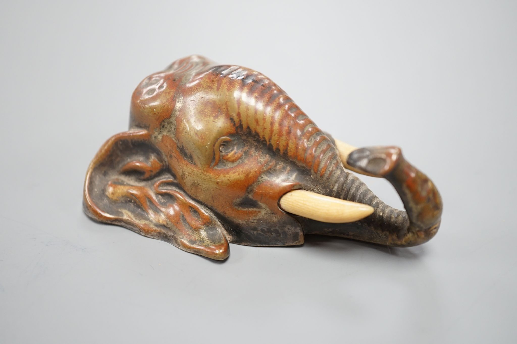 A small bronze elephant paperweight, ivory tusks, 9 cms long.